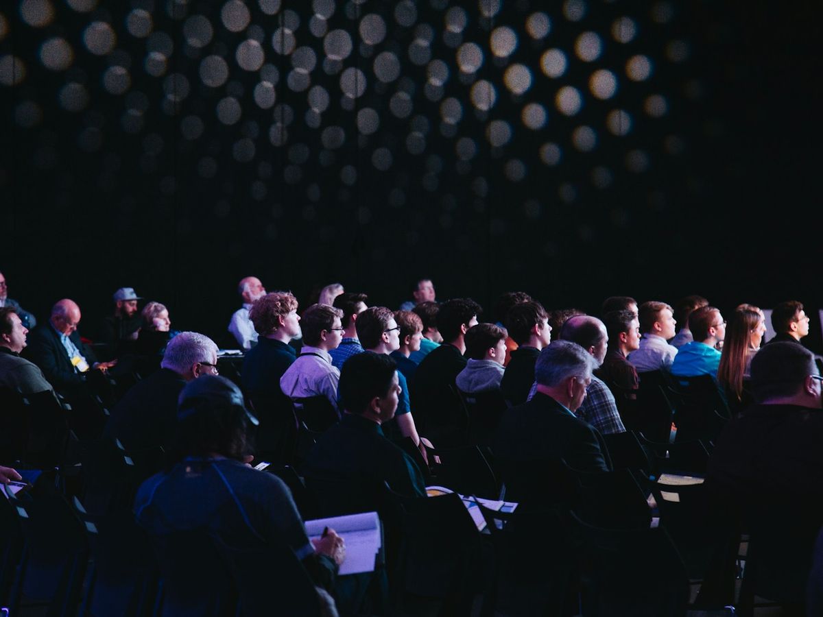 A full event hall watching a presentation on stage