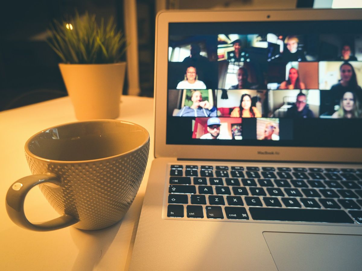 A laptop showing a video call with many participants
