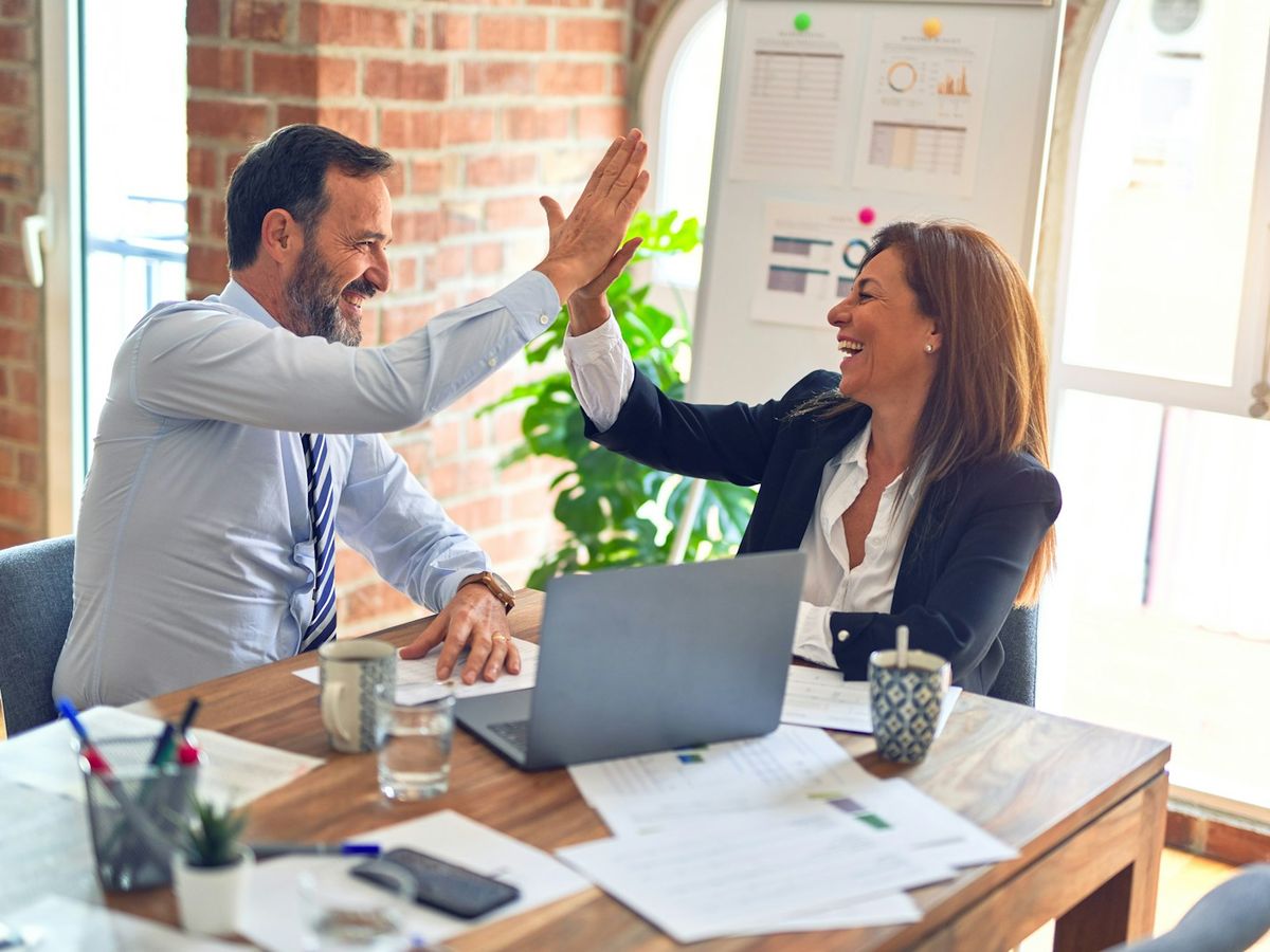 Two new colleagues giving each other a high five in the office